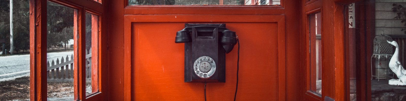 black rotary telephone mounted on red wooden wall